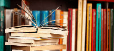 livros empilhados e um deles aberto no meio