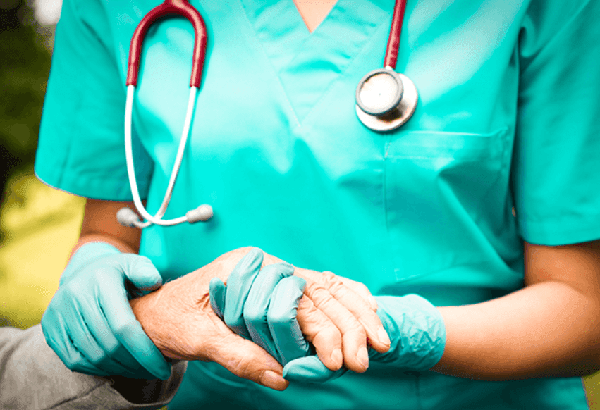 um enfermeiro com luvas pegando na mão de um paciente.